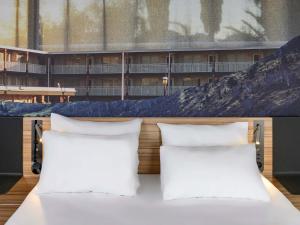 two white pillows sitting on a bed in front of a building at Novotel Saint-Étienne Centre Gare Châteaucreux in Saint-Étienne