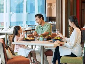 a family sitting at a table in a restaurant at Novotel Hanoi Thai Ha in Hanoi