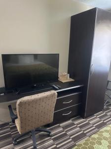 a room with a desk with a television and a chair at Rodeway Inn in Webster