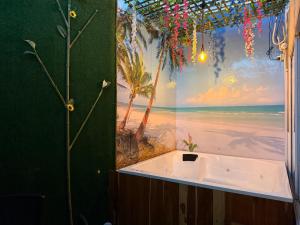 Una bañera en un baño con un mural de una playa. en FULL HOUSE CON JACUZZI y ZONA BBQ, en El Colegio