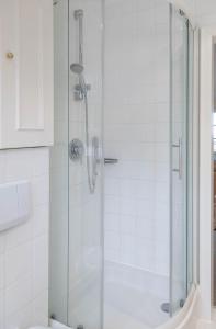 une douche avec une porte vitrée dans une salle de bain dans l'établissement Heefwai-Wohnung-4, à Morsum 9 autres photos