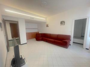 a living room with a red couch and a tv at Casa Caterina in Alassio +1 photo