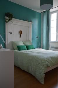 a green bedroom with a bed with green pillows at Le Moulin de Bassac in Bassac