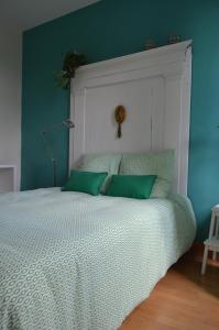 a bedroom with a bed with green and white sheets at Le Moulin de Bassac in Bassac