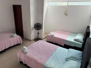 エル・コレヒオにあるFULL HOUSE CON JACUZZI y ZONA BBQのベッド3台とファンが備わる客室です。