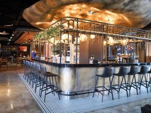a bar with a bunch of stools in a restaurant at Novotel Bishkek City Center in Bishkek