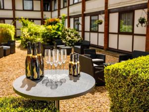 a table with wine bottles and wine glasses on it at The Harlow Hotel By AccorHotels in Harlow