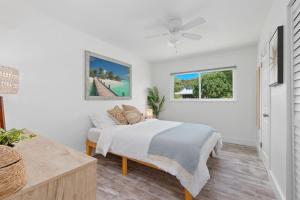 a bedroom with a bed and a couch and two windows at Little Palm Cottage in Vero Beach