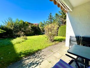 a patio with a table and chairs in a yard at Waldgeflüster, Montana Haus in Oberstdorf