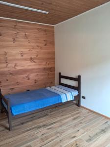 a bed in a room with a wooden wall at Piezas estilo departamento en casa Pucón in Pucón
