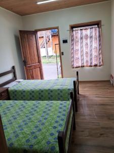 two beds in a room with a door and two windows at Piezas estilo departamento en casa Pucón in Pucón