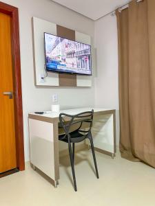 a chair sitting at a desk with a television on the wall at Hotel Ideal 5 in Araguaína