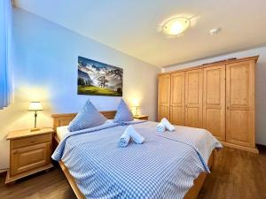 a bedroom with two beds with blue and white sheets at Waldgeflüster, Montana Haus in Oberstdorf +16 photos