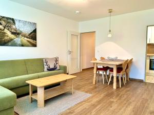a living room with a green couch and a table at Waldgeflüster, Montana Haus in Oberstdorf