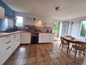 una cucina con mobili bianchi, tavolo e sedie di Maison Équilibre a Royère-de-Vassivière