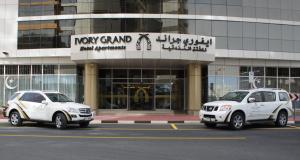 two white cars parked in front of a building at Ivory Grand Hotel Apartments in Dubai