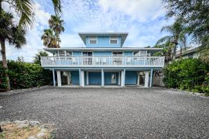 a blue house with a balcony and palm trees at 100' from the beach, Charming 1BR Beachside Retreat in Point O'Rocks