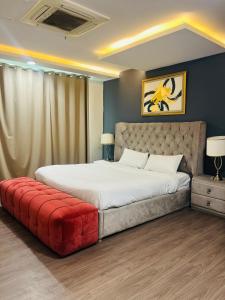 a bedroom with a large bed with a red ottoman at One Bed Appartment in GoldCrest Mall and residency DHA Lahore in Dargai