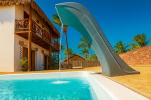 a water slide in a swimming pool in front of a house at Villa Yvytu - Praia do Preá in Prea