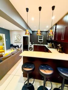 a kitchen with bar stools and a living room at Umoya Executive Apartment in Mbabane