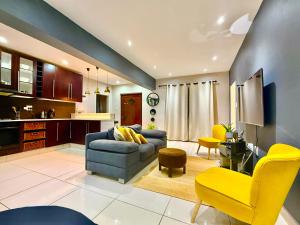 a living room with a blue couch and yellow chairs at Umoya Executive Apartment in Mbabane