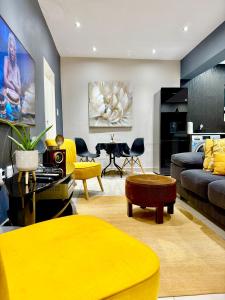 a living room with yellow furniture and a yellow couch at Umoya Executive Apartment in Mbabane