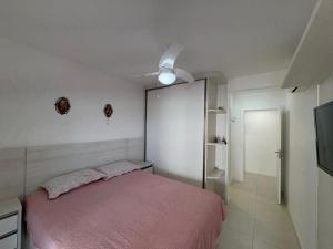 a bedroom with a pink bed and a tv at cód 58 · Apartamento aconchegante in Governador Celso Ramos