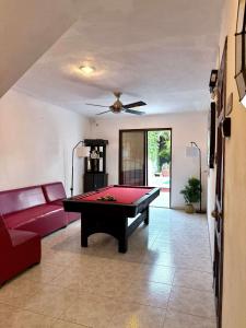 Chuburná de HidalgoAlojamiento tranquilo en Casa con Piscina的客厅设有台球桌和红色沙发。