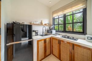 a kitchen with wooden cabinets and a black refrigerator at Wake Up in Nature - Serene Stays at Sarang Apartment 5 in Ubud in Ubud