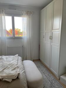 ein weißes Schlafzimmer mit einem Bett und einem Fenster in der Unterkunft Location d un étage d une maison in Savigné-lʼÉvêque