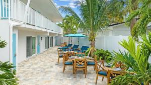 an outdoor patio with tables and chairs and palm trees at Sea Coast - 276 in Siesta Key