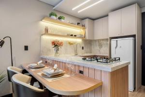 eine Küche mit einem Tisch und einem weißen Kühlschrank in der Unterkunft Condomínio Residencial e Comercial YOU in Canela