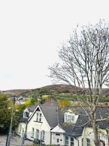 a white house with a fence and a tree at Gaen - Ty Seren in Abertillery