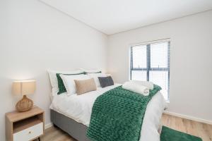 a bedroom with a bed with a green blanket and a window at Modern 2 Bed Home with Solar & Braai Langebaan in Langebaan