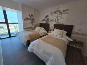 a bedroom with two beds and a large window at HOM I Ideal Depto 2D2B Frente al Mall Antofagasta in Antofagasta