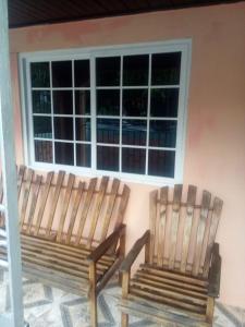 two wooden benches sitting in front of a window at Port Antonio Residence in Port Antonio
