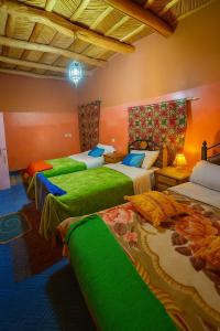a bedroom with three beds with green sheets at DAR Moha dades in Aït Ougliff