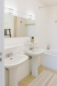a white bathroom with two sinks and a mirror at Parking gratuit, piscine intérieur vue panoramique in Heist +15 photos