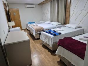 a hotel room with two beds and a desk at Pousada ji Paraná in Ji-Paraná