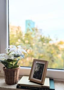 ein Bilderrahmen auf einem Buch neben einem Fenster in der Unterkunft Bella Luna Luxury Suites - Warm & Modern Apt Near Old Town & Museums in Warschau