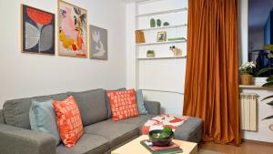 ein Wohnzimmer mit einem grauen Sofa und einem orangenen Vorhang in der Unterkunft Bella Luna Luxury Suites - Warm & Modern Apt Near Old Town & Museums in Warschau + 11 Fotos