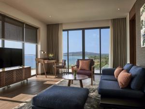 Una sala de estar con un sofá azul y un televisor. en Mövenpick Resort Waverly Phu Quoc, en Phu Quoc