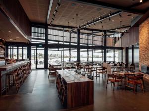 a restaurant with wooden tables and chairs and windows at The Sebel Yarrawonga Silverwoods in Yarrawonga