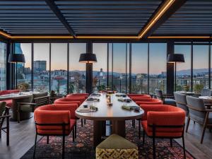 Un restaurante con mesas y sillas y grandes ventanales. en Swissôtel Tbilisi, en Tiflis