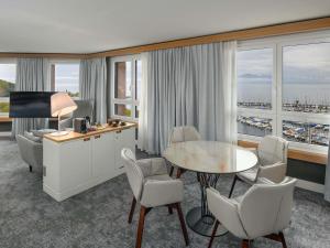 a hotel room with a table and chairs and a desk at Mövenpick Hotel Lausanne in Lausanne