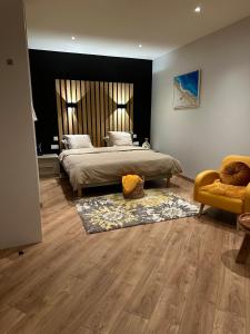 ein Schlafzimmer mit einem großen Bett und einem gelben Stuhl in der Unterkunft Chambre privée avec salle de bain in Domagné