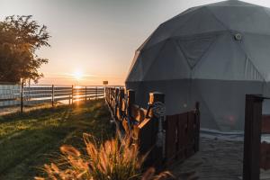 a tent with the sun setting behind a fence at Waterfront Glamping - Private hot tube, sauna & sunset view in Wapnica +23 photos