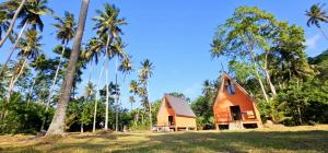 a small house in a field with palm trees at Beach Cabanas Hiriketiya in Hiriketiya