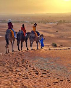 a group of people riding horses in the desert at Merzouga Standard Camp in Merzouga