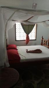 1 dormitorio con cama con dosel y pescado en Watamu villas, en Watamu